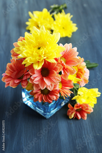 Chrysanthemum flowers in vase on wooden table close-up