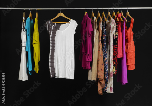 Variety of casual fashion clothing hanging on hangers on black © inchic