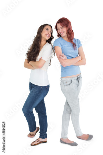 Full length of two female friends with arms crossed