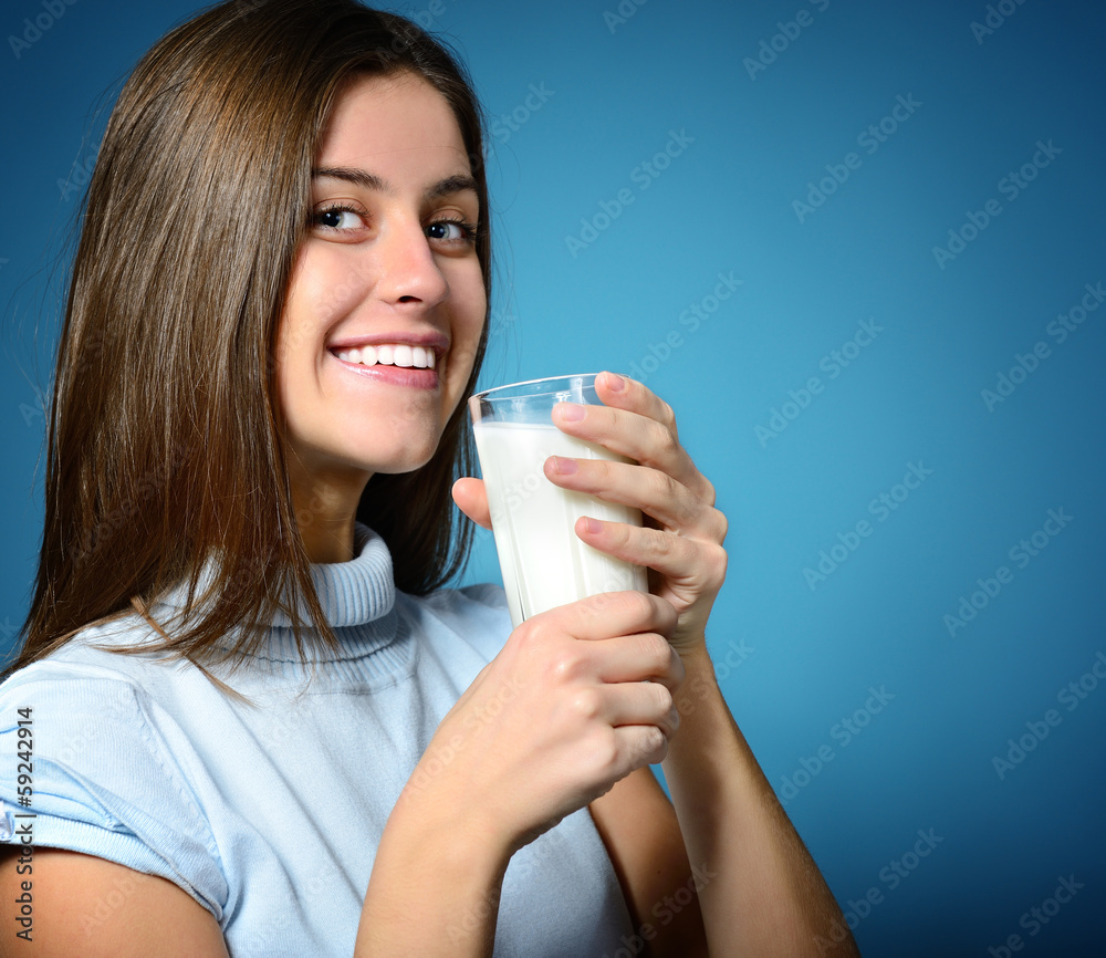 beautiful cheerful teen girl drinking milk over blue Stock Photo