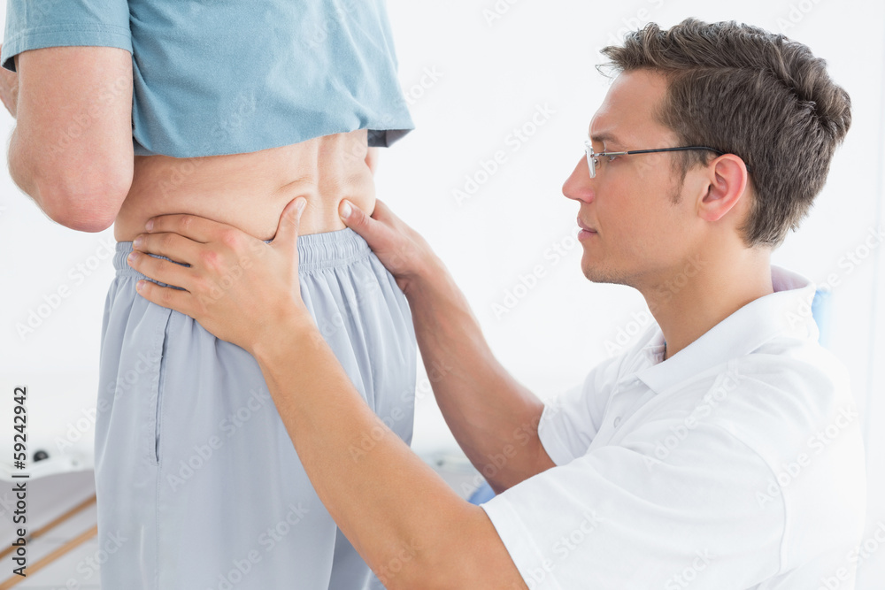 Male therapist massaging mans lower back in gym hospital Male therapist massaging mans lower back in gym hospital