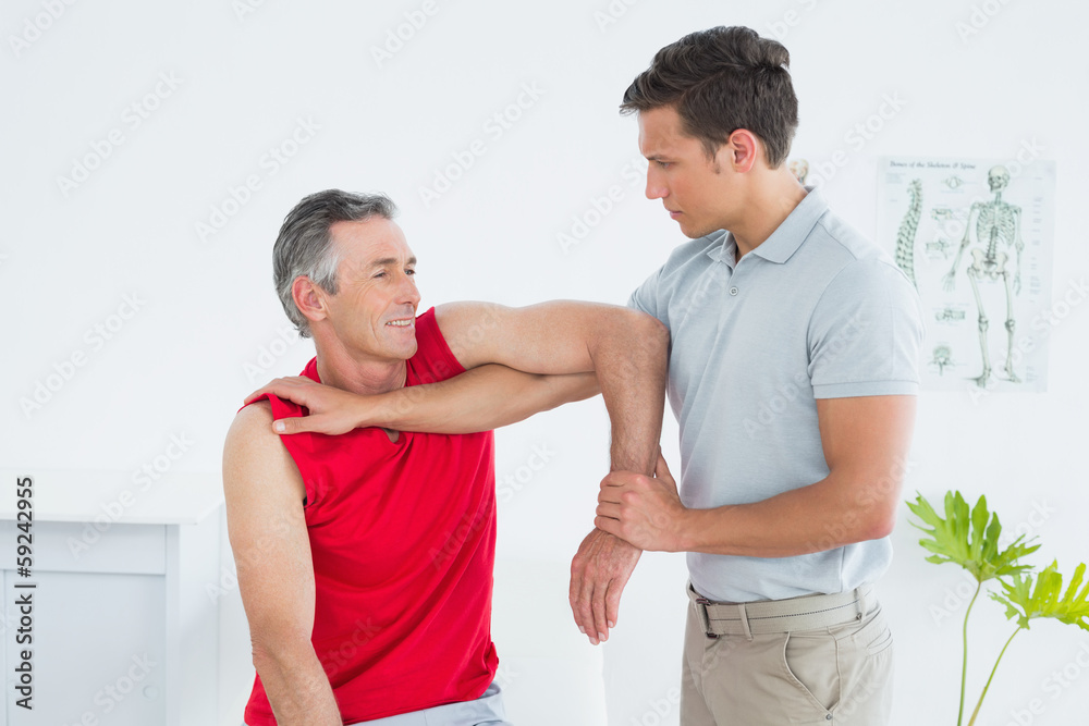 Male physiotherapist stretching a mature mans arm Male physiotherapist stretching a mature mans arm