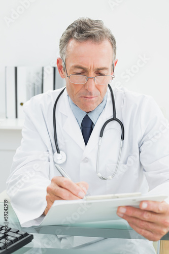 Doctor writing a report at desk in medical office