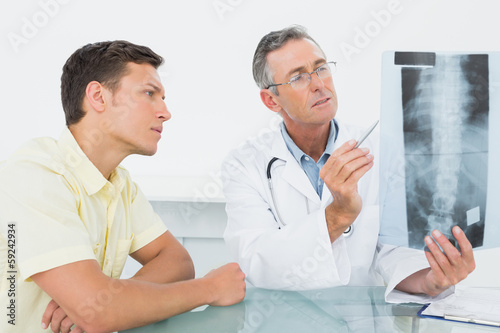 Doctor explaining spine x-ray to patient in office