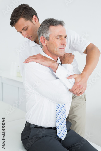 &lt;ale chiropractor examining mature man