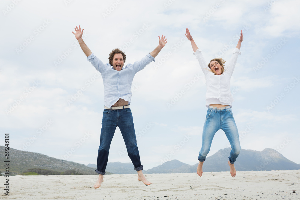 Cheerful young couple jumping at beach Cheerful young couple jumping at beach