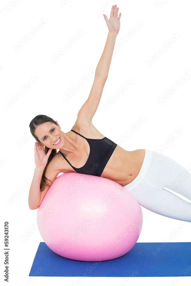 Fototapeta premium Portrait of a fit woman stretching on fitness ball