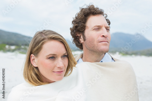 Couple wrapped in blanket at beach