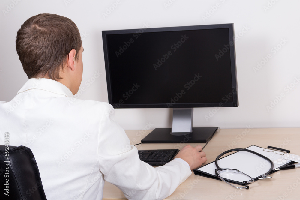 young male doctor using personal computer in office