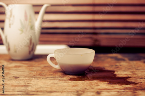 Coffee cup and pot by window on wood table