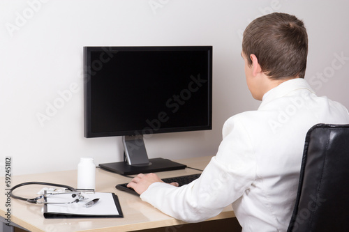 young male doctor working with computer in office