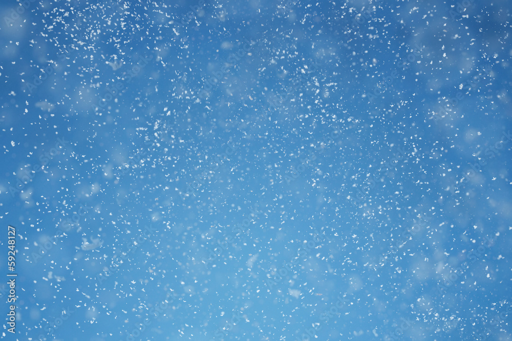 Fototapeta premium Falling snow over blue background with copy space