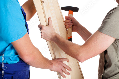 Two men with plank and hammer