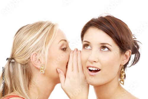 two smiling women whispering gossip