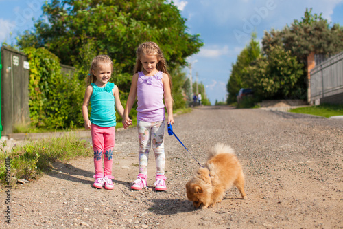 Two Little girls walking with small ??dog on a leash outdoor