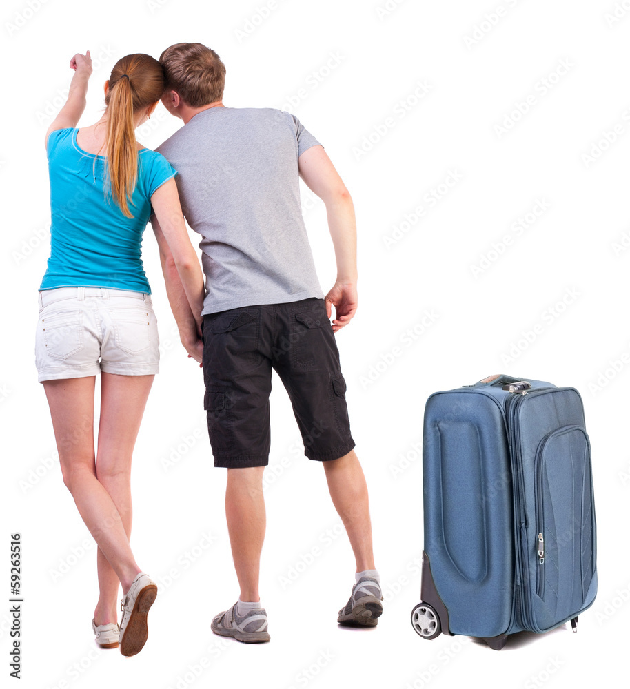 young couple traveling with suitcas and pointing at wal Back vie young couple traveling with suitcas and pointing at wal Back vie