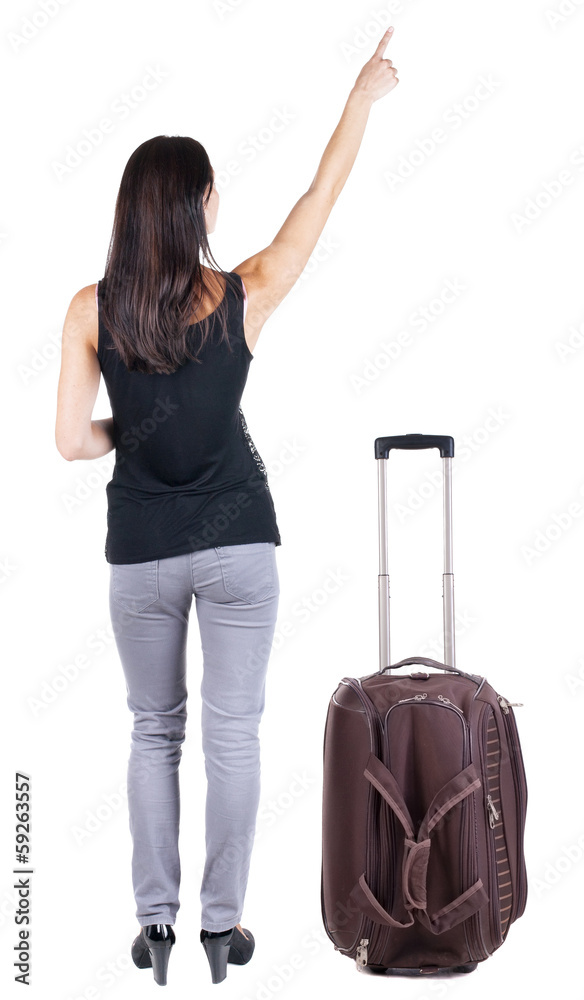 Back view of young brunette woman traveling with suitcas and poi Back view of young brunette woman traveling with suitcas and poi