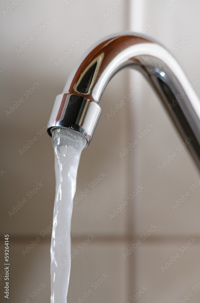 Vertical image of a tap with water flowing normally Vertical image of a tap with water flowing normally