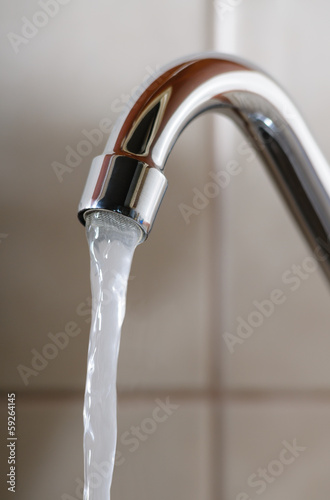 Vertical image of a tap with water flowing normally