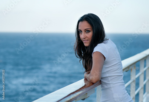 Woman standing next to a railing with seascape background