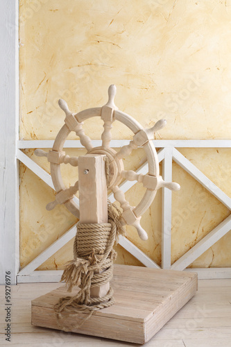 Beautiful wooden ship wheel with wire rope in light room photo