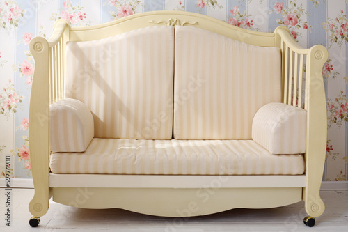 Beautiful light yellow small sofa in bright empty simple room.