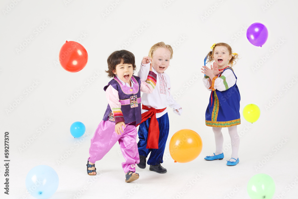 Little girl and two boys in folk costumes play with balloons