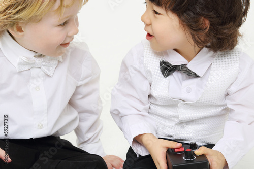 Little boy holds control console and blond boy looks at he