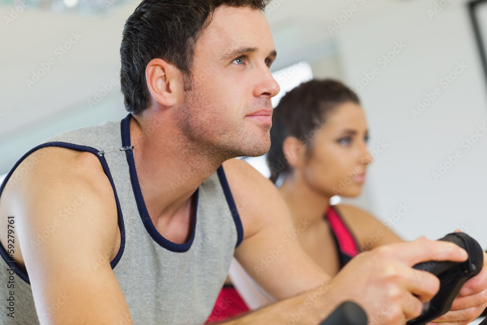 Fototapeta premium Yyoung man and woman working out at spinning class