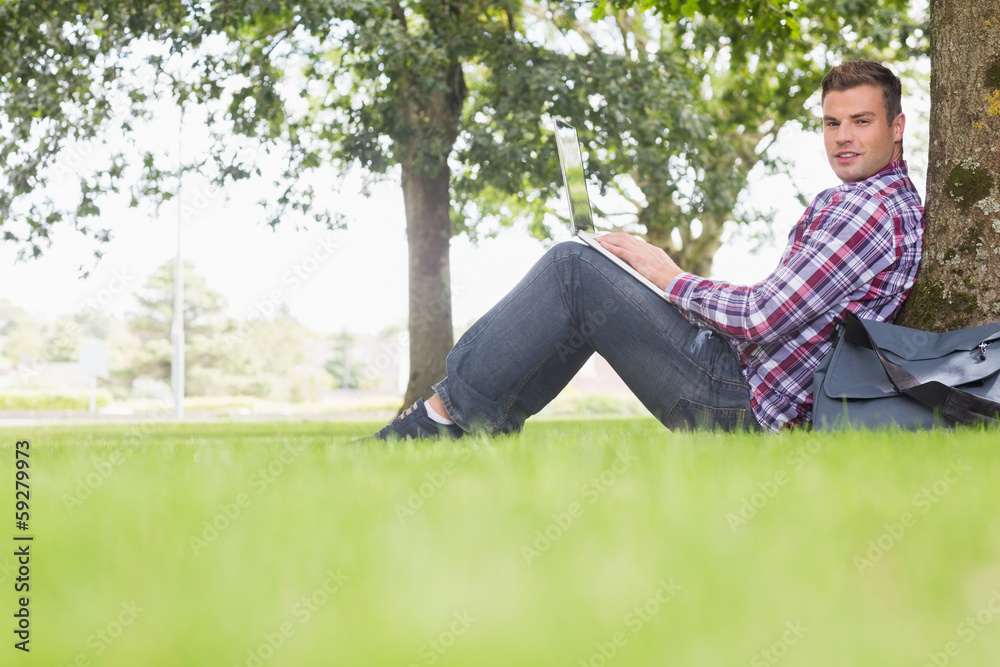 Happy student using his laptop to study outside Happy student using his laptop to study outside