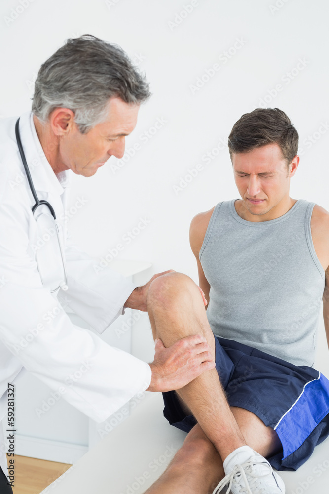 Obraz premium Displeased young man getting his leg examined
