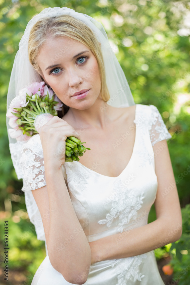 Pretty bride holding her bouquet wearing a veil Pretty bride holding her bouquet wearing a veil