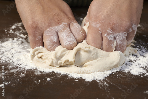 woman's hands kneading dough on wooden table