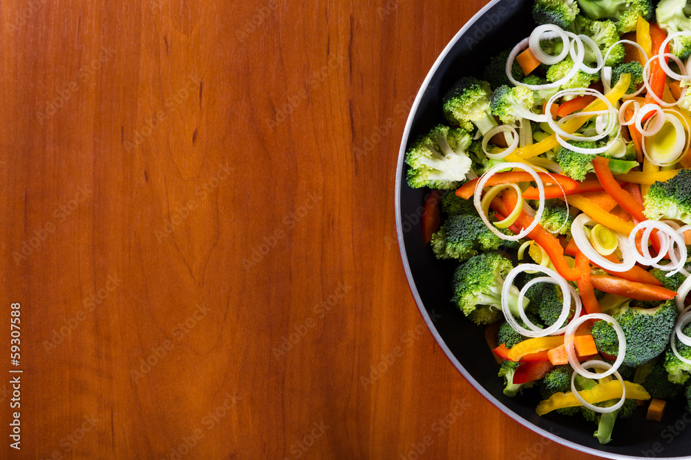 frying vegetables in pan with wood background frying vegetables in pan with wood background