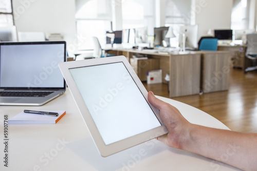 Person in the office holding a touch screen device.