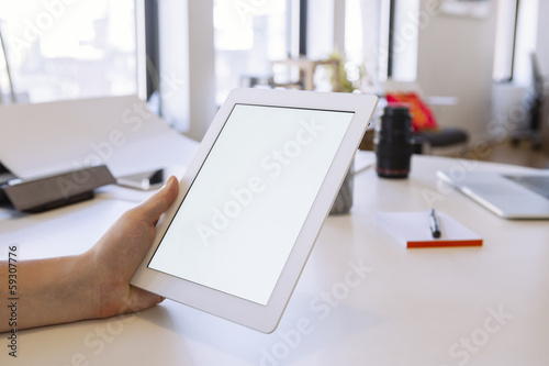 Person in the office holding a touch screen device.