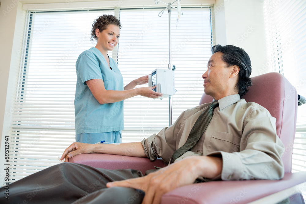 Obraz premium Nurse Looking At Patient While Adjusting IV Machine