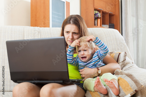 sorehead mother with crying baby working online photo