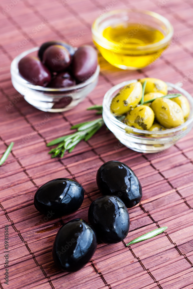 Plates of green olives, black olives and olive oil on bamboo nap Plates of green olives, black olives and olive oil on bamboo nap