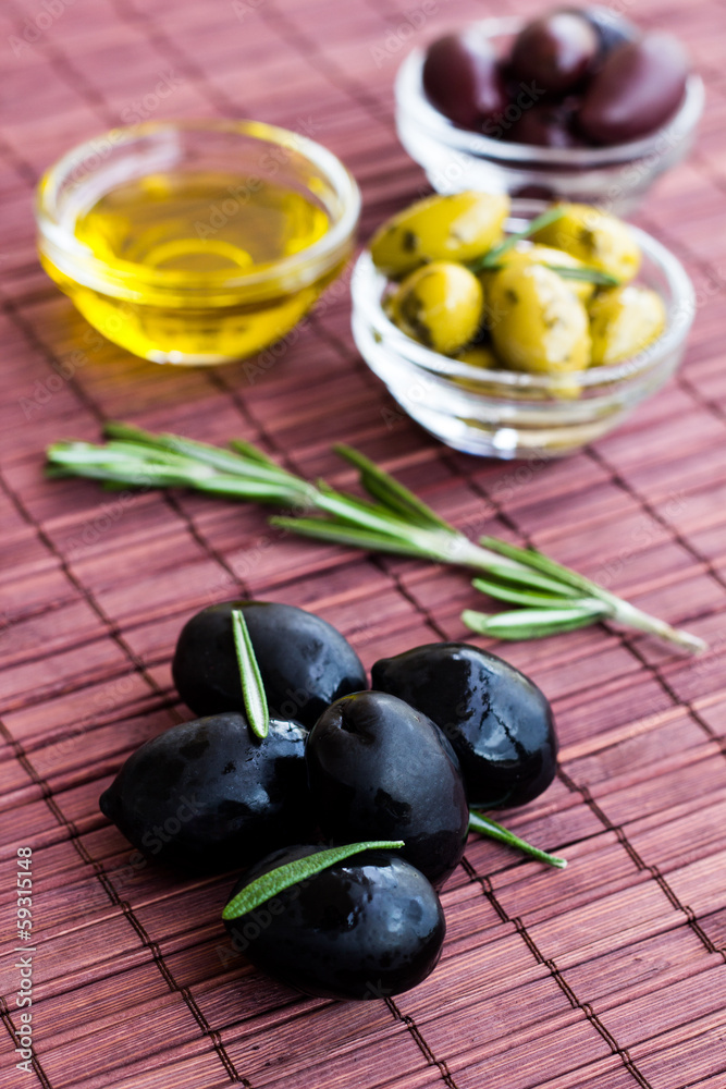 Plates of green olives, black olives and olive oil on bamboo nap Plates of green olives, black olives and olive oil on bamboo nap