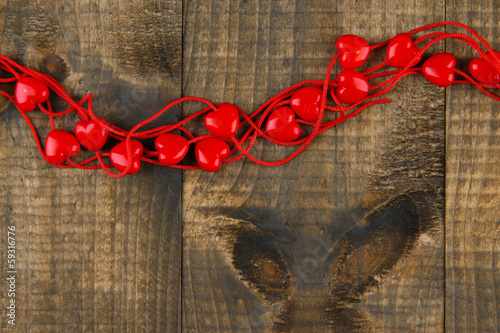 Heart-shaped beads on string on wooden background