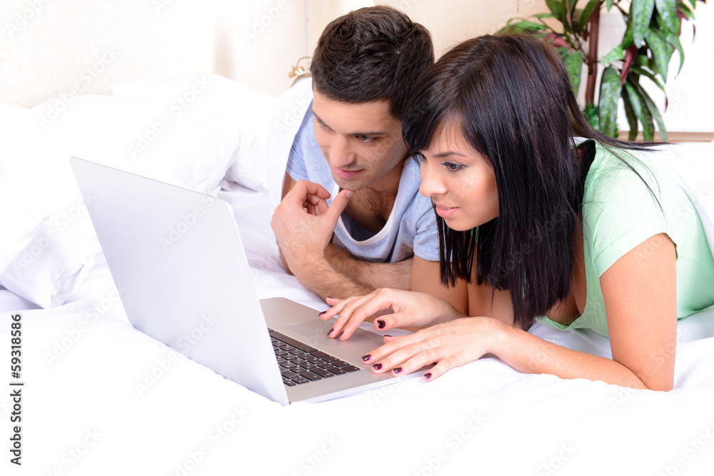 Couple in love with laptop in bed Couple in love with laptop in bed