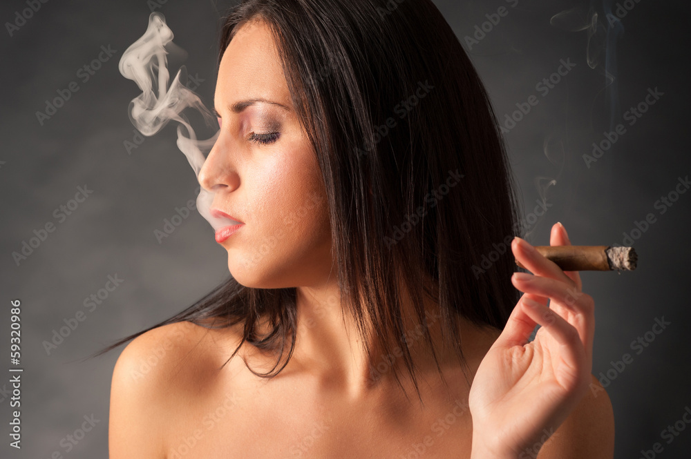 Obraz premium Portrait of woman smoking cigar. Studio fashion photo on dark ba