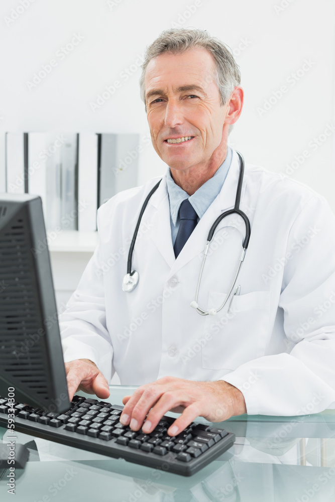 Smiling male doctor using computer at office Smiling male doctor using computer at office