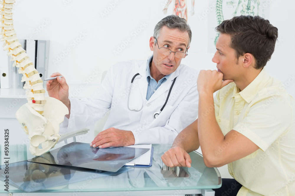 Doctor explaining spine to patient in office Doctor explaining spine to patient in office