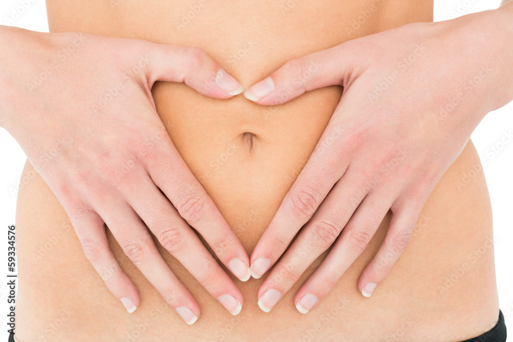 Mid section of a fit woman with hands over belly