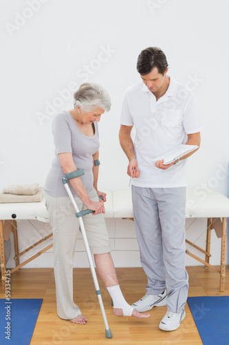 Male therapist examining disabled senior patient' leg