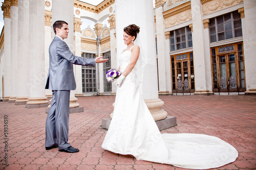 groom giving hand to beautiful bride in dress with long loop
