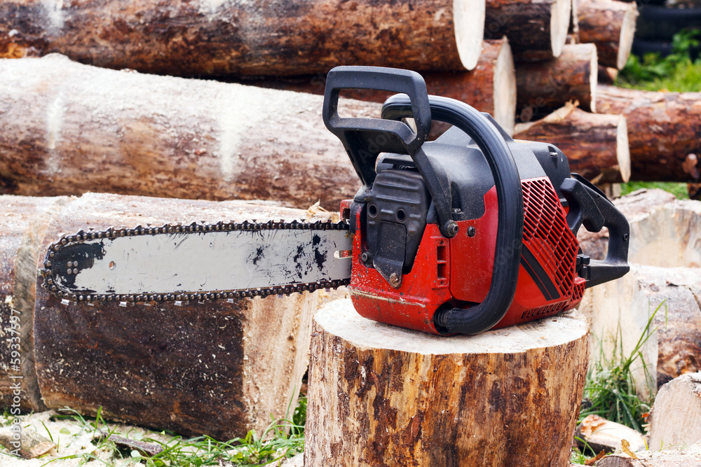 Powered professional chainsaw on pile of cut wood