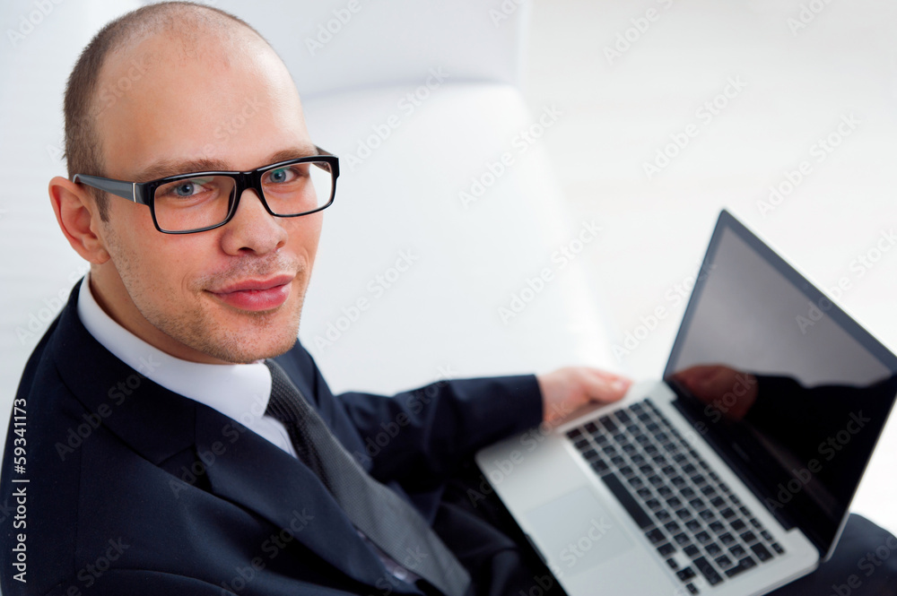 Young smiling businessman sitting with laptop Young smiling businessman sitting with laptop